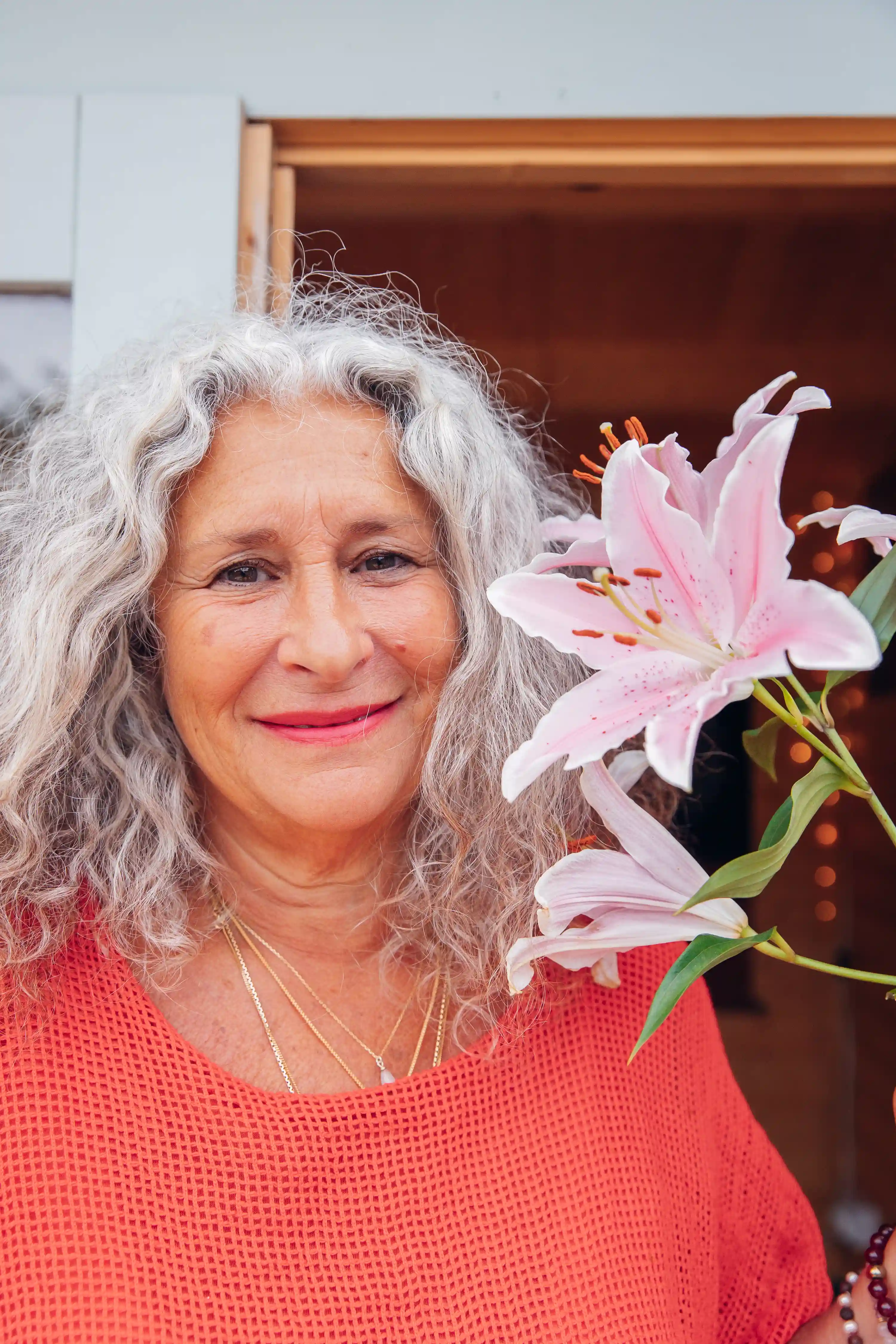 Image of Jyoti standing in her studio with a flower.